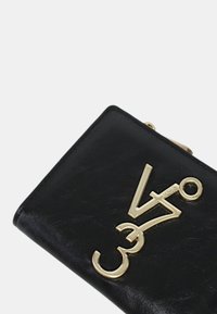 Portafoglio in pelle nera con una finitura testurizzata, caratterizzato da un accento dorato con logo e una chiusura a scatto. Design compatto e rettangolare.