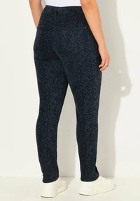 Leggings azul oscuro con un patrón de hojas, fabricados con un material elástico. Presentan una cintura alta y bolsillos traseros. Costuras planas.