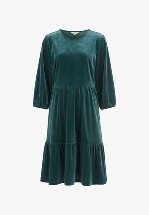 Velvet grøn kjole med rund halsudskæring, lange ærmer og lagdelt, udvidet nederdel. Blød tekstur med elastiske manchetter ved ærmerne.