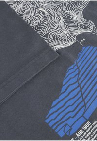 Czarna koszulka z ciemnoszarego materiału z białymi liniami topograficznymi i niebieskimi paskowymi grafikami. Napis w kolorze białym umieszczony na dole. Materiał bawełniany.