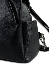 Sac à main en cuir texturé noir avec fermeture éclair en métal argenté et fermoir, doté d'une poche latérale et d'une bandoulière ajustable, sur fond blanc.