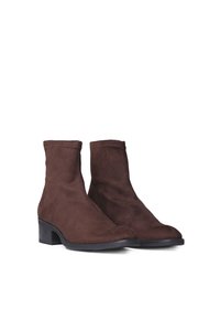 Botines de ante marrón con un tacón bajo y cuadrado, que presentan un diseño elegante y detalles de costura a lo largo de las costuras. Textura suave, sin cierres.