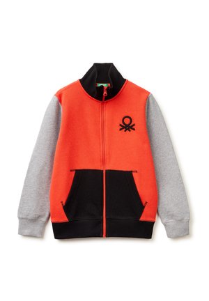 Giacca con zip per bambino, con corpo arancione, maniche grigie, colletto nero, tasche anteriori nere e un piccolo logo nero sul petto.