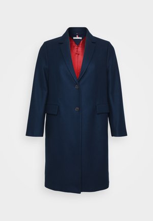 Navy blue long coat with a single button closure and two front pockets, featuring a red lining visible at the collar and opening.
