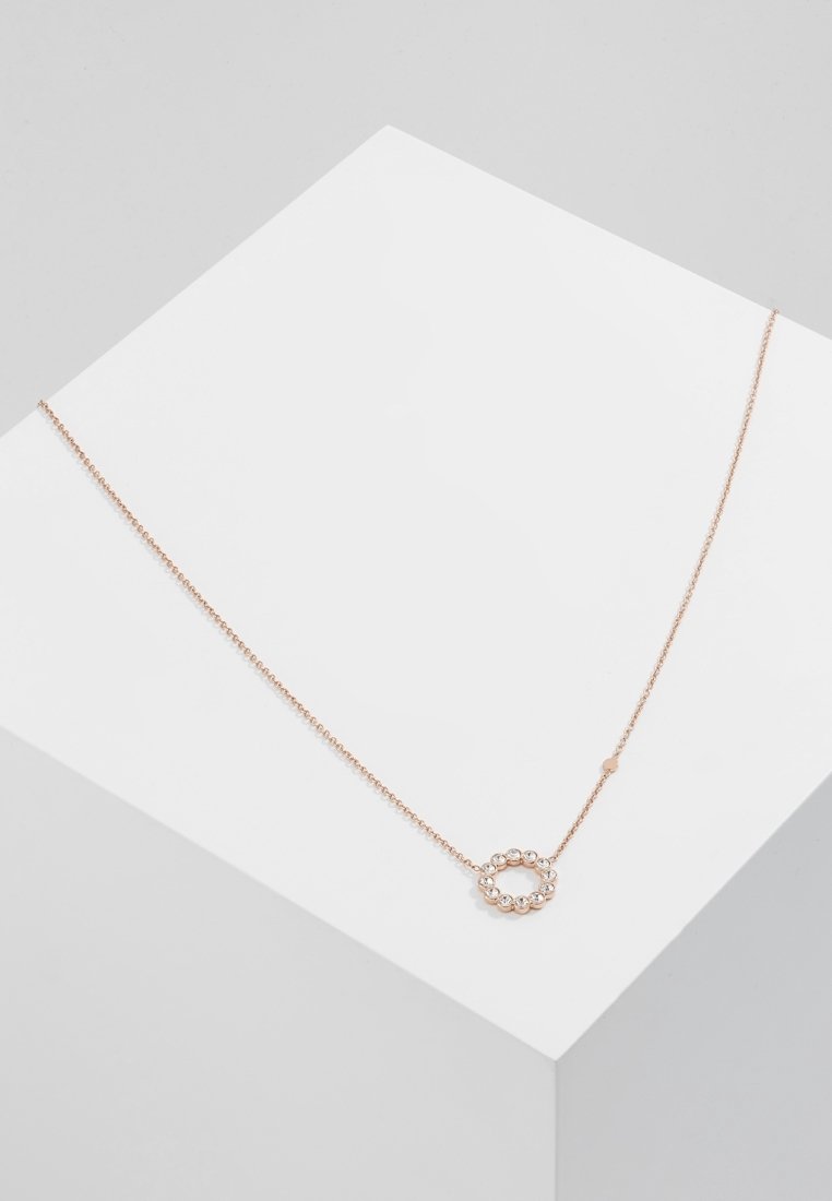 Collier délicat en chaîne en or rose avec un petit pendentif circulaire composé de cristaux ronds régulièrement espacés, présenté sur une surface géométrique blanche.