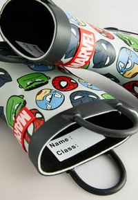 Bottes de pluie sur le thème de Marvel avec une base blanche, ornées de visages de super-héros en cartoon colorés. Bords en caoutchouc noir et deux poignées pour un enfilage facile.