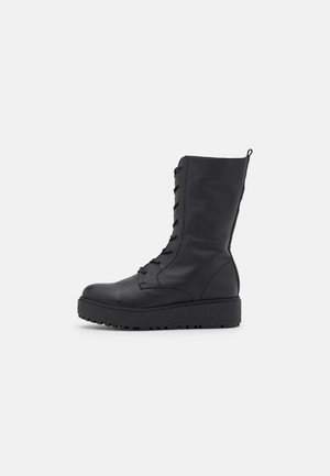 Bottes noires à lacets avec une tige haute, en cuir texturé, dotées d'une semelle plateforme épaisse et d'une languette arrière pour un enfilage facile.