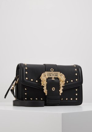 Bolso bandolera negro de Versace Jeans Couture con detalles de tachuelas doradas y hebilla dorada ornamentada en la solapa delantera.
