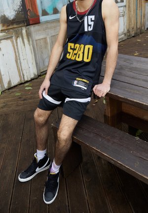 Canotta da basket Nike nera con "5280" in giallo, abbinata a pantaloni corti neri con strisce laterali bianche e sneaker nere con accenti viola.