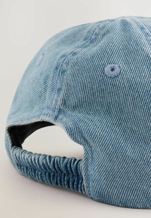 Cappello in jeans di colore azzurro chiaro, con visiera curva, retro elasticizzato arricciato e dettagli cuciti. La texture è a coste con un interno liscio.