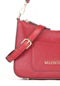 Borsa a spalla in pelle rossa con finitura texturizzata, dotata di una fibbia in metallo dorato, chiusura con zip e logo del marchio impresso.