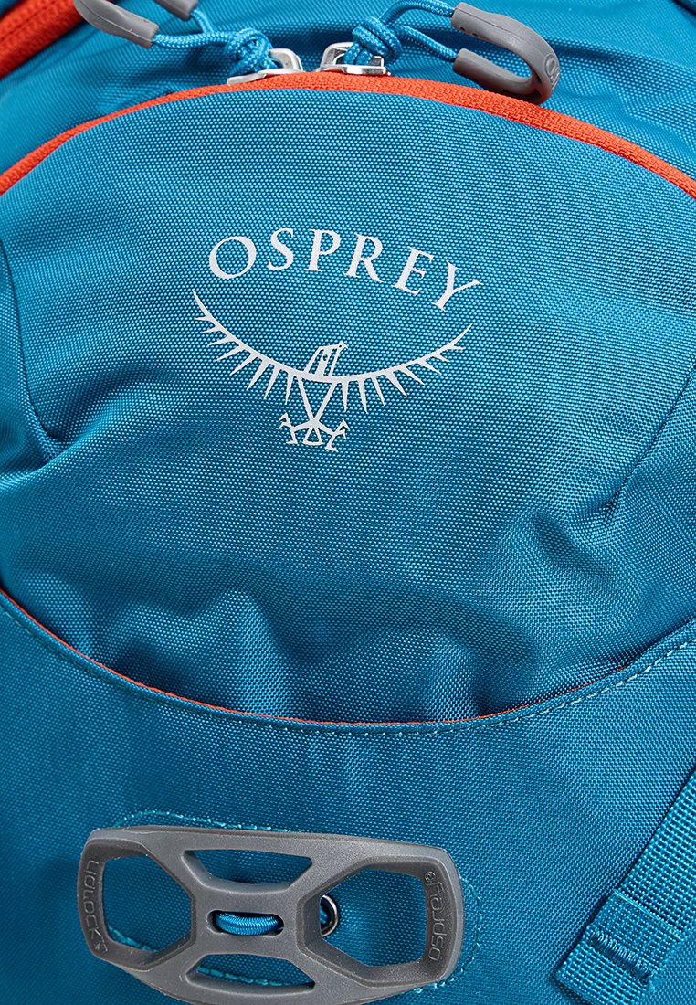 Teal ryggsäck med en framträdande vit Osprey-logotyp, orange dragkedjeaccenter och en grå hårdvaruklämma för fäste eller säkring av föremål.