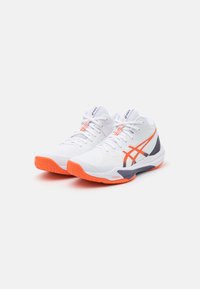 Witte sportieve schoenen met oranje accenten en grijze details. Beschikt over een gestructureerde bovenkant, opvallende veters en een gevoerde zool.