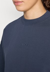 Marineblaue Sweatshirt mit Rundhalsausschnitt und gesticktem "BORG"-Logo in passendem Faden. Weicher Baumwollstoff, lässige Passform.