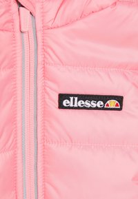 Giacca gonfiabile rosa con texture trapuntata, dotata di una cerniera grigia e un'etichetta nera con lettering bianco e un emblema.