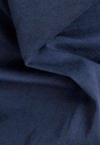 Granatowy materiał o gładkiej strukturze, z delikatnym prążkowanym wzorem i miękkim opadaniem, podkreślający swoją lekkość i elastyczność.