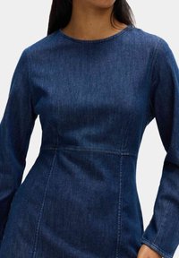 Mörkblå denimklänning med rund halsringning och långa ärmar, som har en figursydd bodice och sömnadsdetaljer. Slät textur.