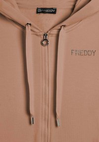 Felpa leggera rosa chiaro con zip, realizzata in morbido tessuto, con zip argentata e strass decorativi che formano la scritta "FREDDY" sul lato sinistro del petto.