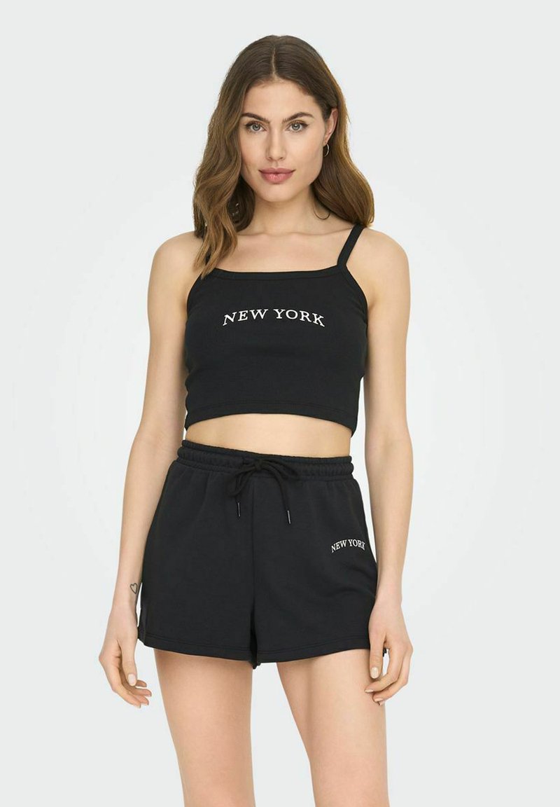 Svart bomulls crop top med spaghetti stropper og hvit "NEW YORK" tekst, paret med matchende svarte drawstring-shorts som har lignende tekst.