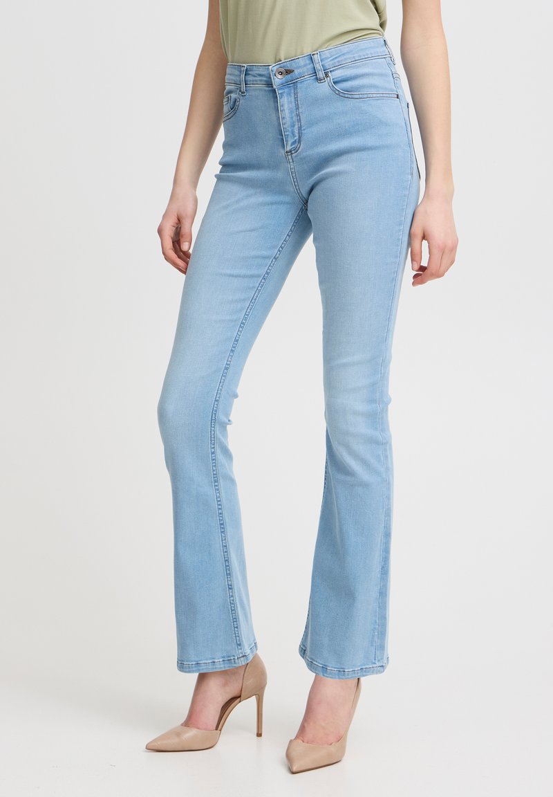 Jean flare bleu clair en denim, avec des poches classiques, une fermeture à bouton et des détails de couture subtils le long des coutures.
