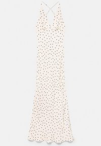 Robe maxi blanche sans manches à pois noirs, col en V profond et fines bretelles croisées dans le dos.
