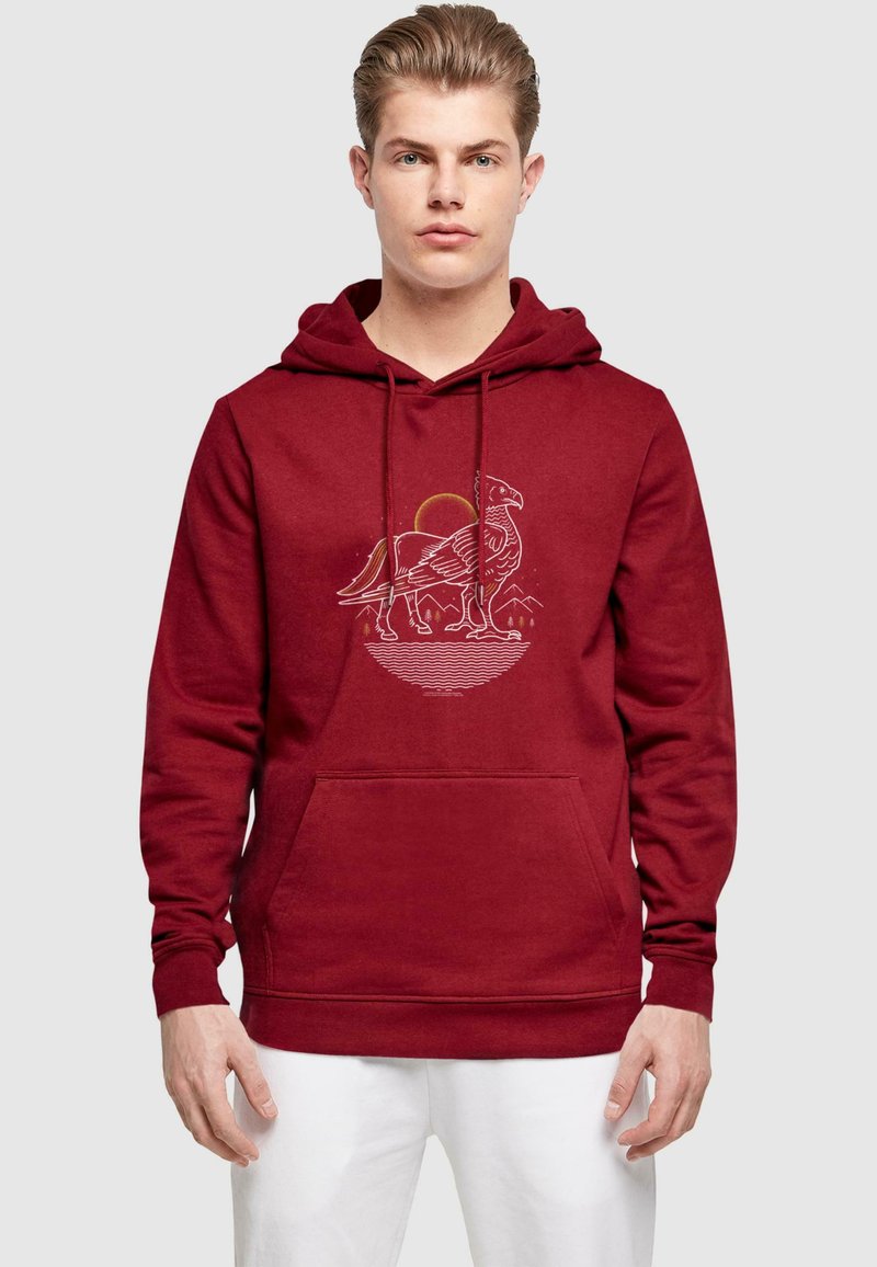 Burgundy hoodie i mjukt material med en framficka och en grafisk bild av en fågel mot en sol och berg, med ribbade ärmslut.