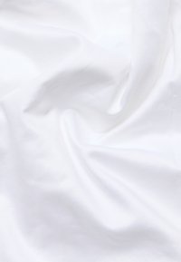 Witte katoenen stof met een gladde textuur, met een subtiel diagonale weefpatroon, gedrapeerd en zacht gekreukt.