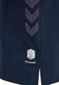 Mörkblå bomulls-T-shirt med vitt zigzag-mönster, med logotyp och varunamn tryckt på nedre vänstra sidan. Rak skärning, korta ärmar.