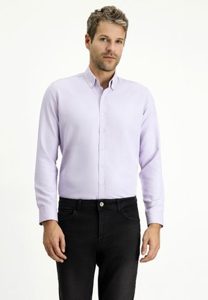 Helles lila Hemd mit langen Ärmeln, glatter Oberfläche und Kragen, kombiniert mit schwarzen Jeans mit einem silbernen Knopf am Bund.