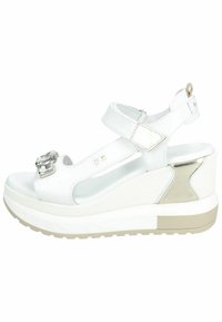 Sandali wedge bianchi con dettaglio della fibbia lucida, cinturini in pelle e accenti testurizzati. Presentano una suola piattaforma con una base marrone chiaro.