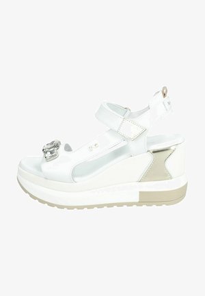Sandales compensées blanches avec un détail en boucle brillante, des brides en cuir et des accents texturés. Comportent une semelle plateforme avec une base marron clair.