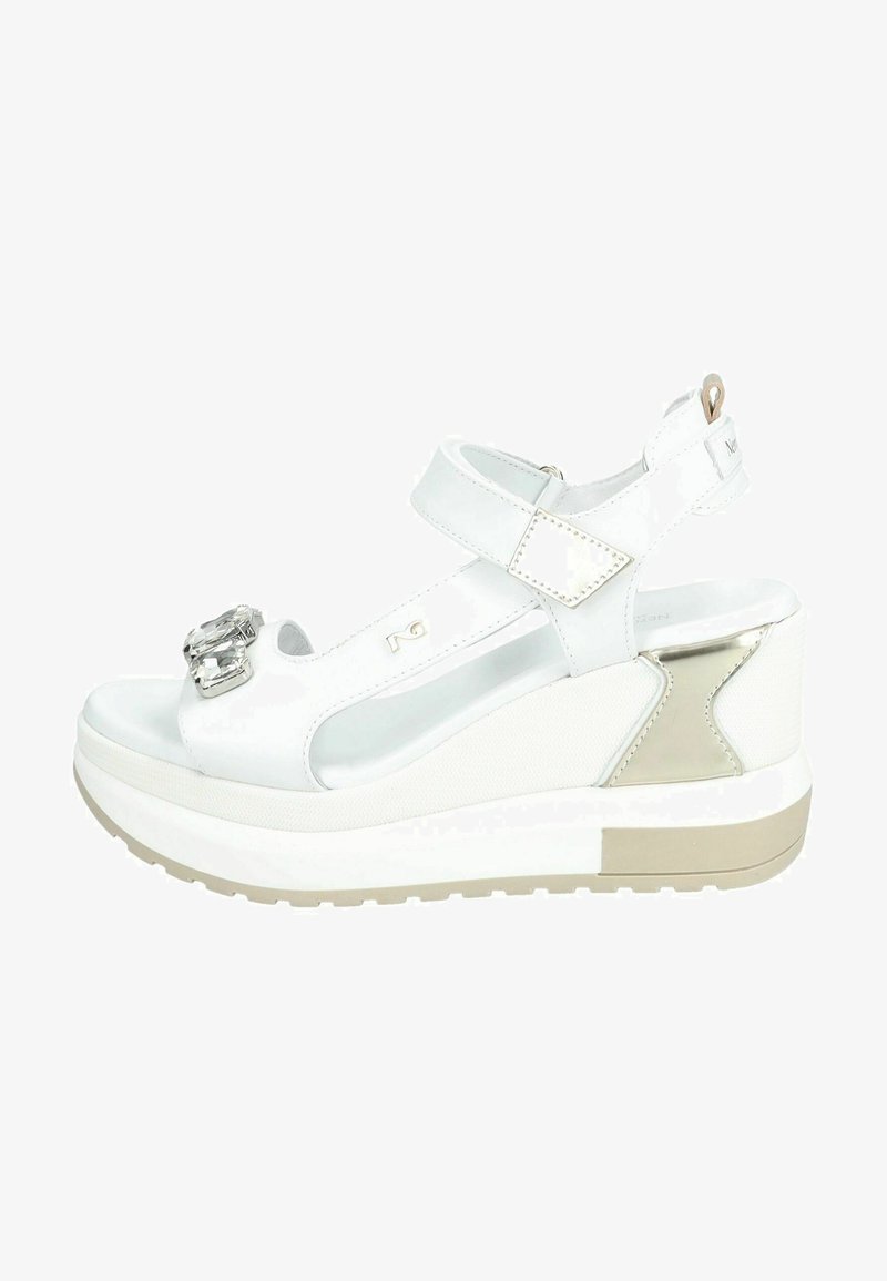 Hvide kilehæle med en skinnende spænde detalje, læderstropper og teksturerede accenter. Har en platformsål med en lys brun bund.