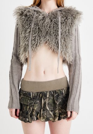 Pull tricoté raccourci avec un panneau en peluche sur la poitrine et des cordons de serrage, associé à une minijupe à motif camouflage avec poches.