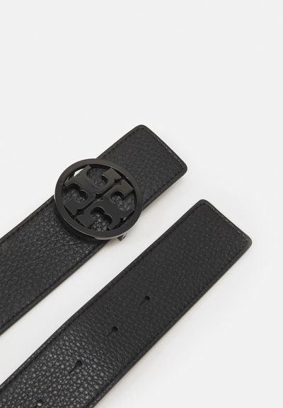 Ceinture en cuir noir avec une sangle texturée et une boucle en forme ovale avec un motif découpé. Le design est simple et moderne.