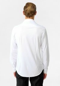 Witte lange mouw shirt van gladde stof met een gebogen zoom, manchet met ééndelige knop en een klassieke kraag. Eenvoudig en op maat gemaakt ontwerp.