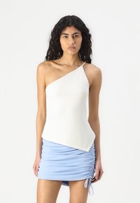 Asymmetrical white top with one shoulder strap, paired with a ruched light blue mini skirt featuring adjustable side ties. Smooth fabric texture.