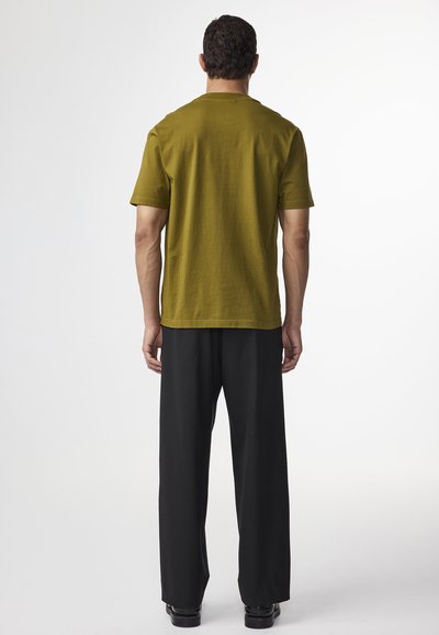 Olivengrøn T-shirt med korte ærmer, blødt bomuldsstof, afslappet pasform. Kombineret med sorte, bredbenede bukser, glat tekstur og elegant design.