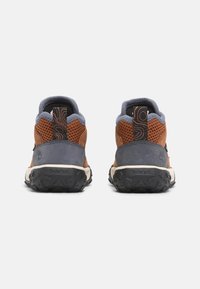 Zapatos de senderismo marrones y grises con paneles de malla, suelas texturizadas y acentos de logo distintivos. Tiras ajustables para facilitar el uso.