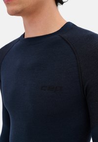 Donkerblauwe thermoshirt met lange mouwen, slim fit, van textuurstof, raglanmouwen en subtiele branding bij de hals.