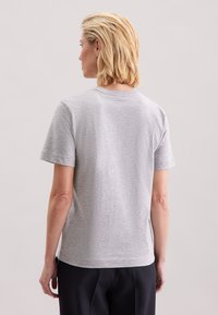 Grå t-shirt med korte ærmer, lavet af et blødt stof. Rundet halsudskæring og sideslidser ved kanten for ekstra komfort og pasform.