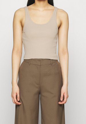 Top ajustado de color beige hecho de tela elástica, combinado con pantalones de pierna ancha de talle alto en color marrón. Diseño sencillo sin patrones visibles.