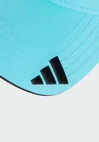 Een lichtblauwe pet met een gebogen klep, voorzien van zwarte gestikte details en een opvallend zwart Adidas-logo aan de zijkant.