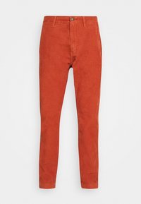 Pantalons en velours côtelé slim fit couleur rouille avec fermeture à bouton et zip sur le devant, passants de ceinture et poches latérales sur fond blanc.