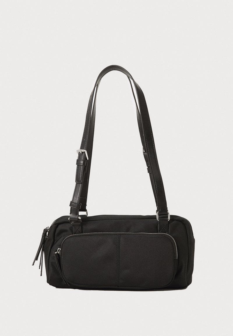 Μαύρη τσάντα από νάιλον με δομημένο σχήμα. Διαθέτει ρυθμιζόμενες δερμάτινες ιμάντες, μπροστινή τσέπη με φερμουάρ και διακριτικά υφασμάτινα στοιχεία.