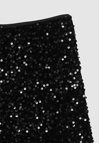 Tessuto nero coperto da paillettes nere e argento lucenti, creando una superficie testurizzata. Il bordo superiore è rifinito con un bordo nero.