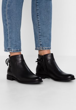 Bottines en cuir noir avec une finition lisse, fermetures éclair sur le côté et lacets décoratifs à l'arrière ; talons empilés bas et orteils arrondis.