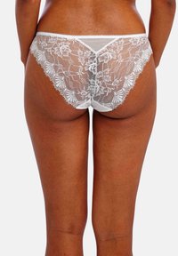 Weiße Spitzenunterwäsche mit floralem Muster, die ein transparentes Rückenteil und einen weichen Bund aufweist, und dabei zarte Texturen und filigrane Details betont.