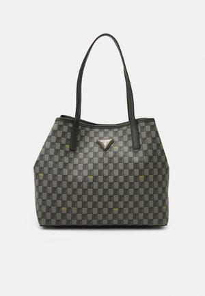 Schwarze und graue karierte Tragetasche mit langen schwarzen Griffen und kleinen gelben "GUESS"-Logos, mit einer silbernen dreieckigen Guess-Logo-Plakette.