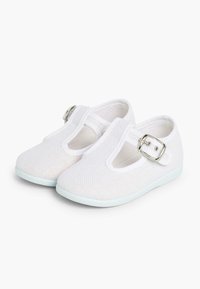 Pantofii din plasă alba au un design cu curea T și o cataramă argintie, având o talpă de un albastru deschis. Aceștia au o textură netedă și vârful închis.