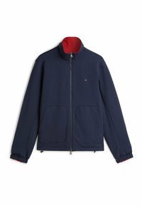 Granatowa kurtka zapinana na zamek z czerwoną wewnętrzną stójką, dwoma przednimi kieszeniami, elastycznymi mankietami oraz małym haftowanym logo na piersi.
